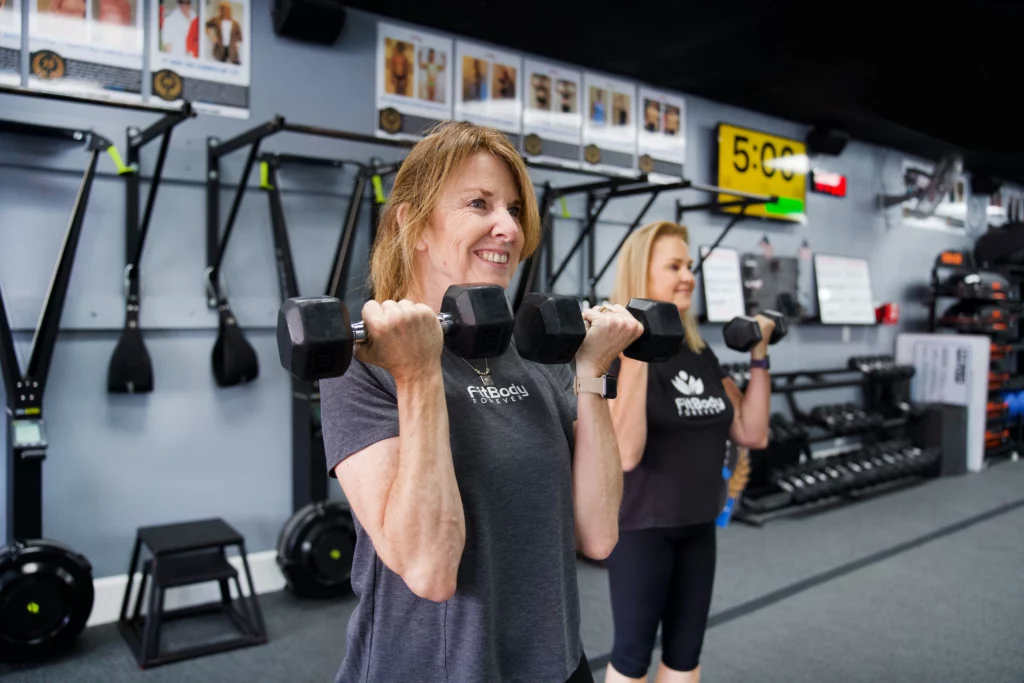 Two women lifting weights at Fit Body Boot Camp