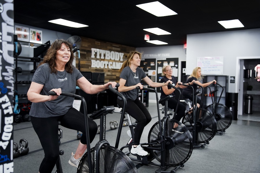 Group of women working out cardio zone on gym bikes.