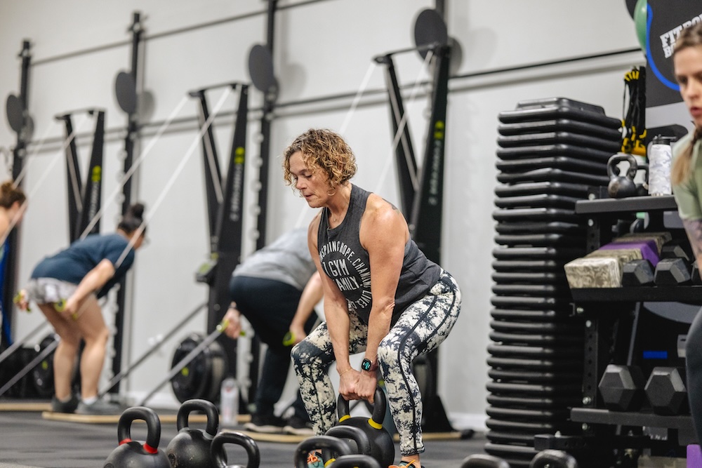 Woman lifting a kettle bell during a 30-minute HIIT session at Fit Body Boot Camp.