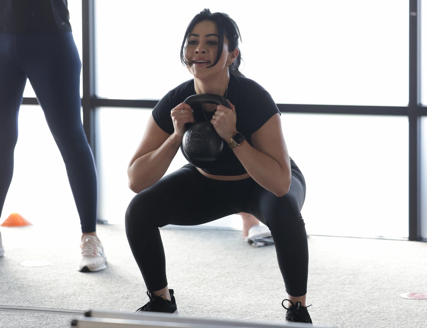 Woman in a Fit Body Boot Camp workout performing a goblet squat.