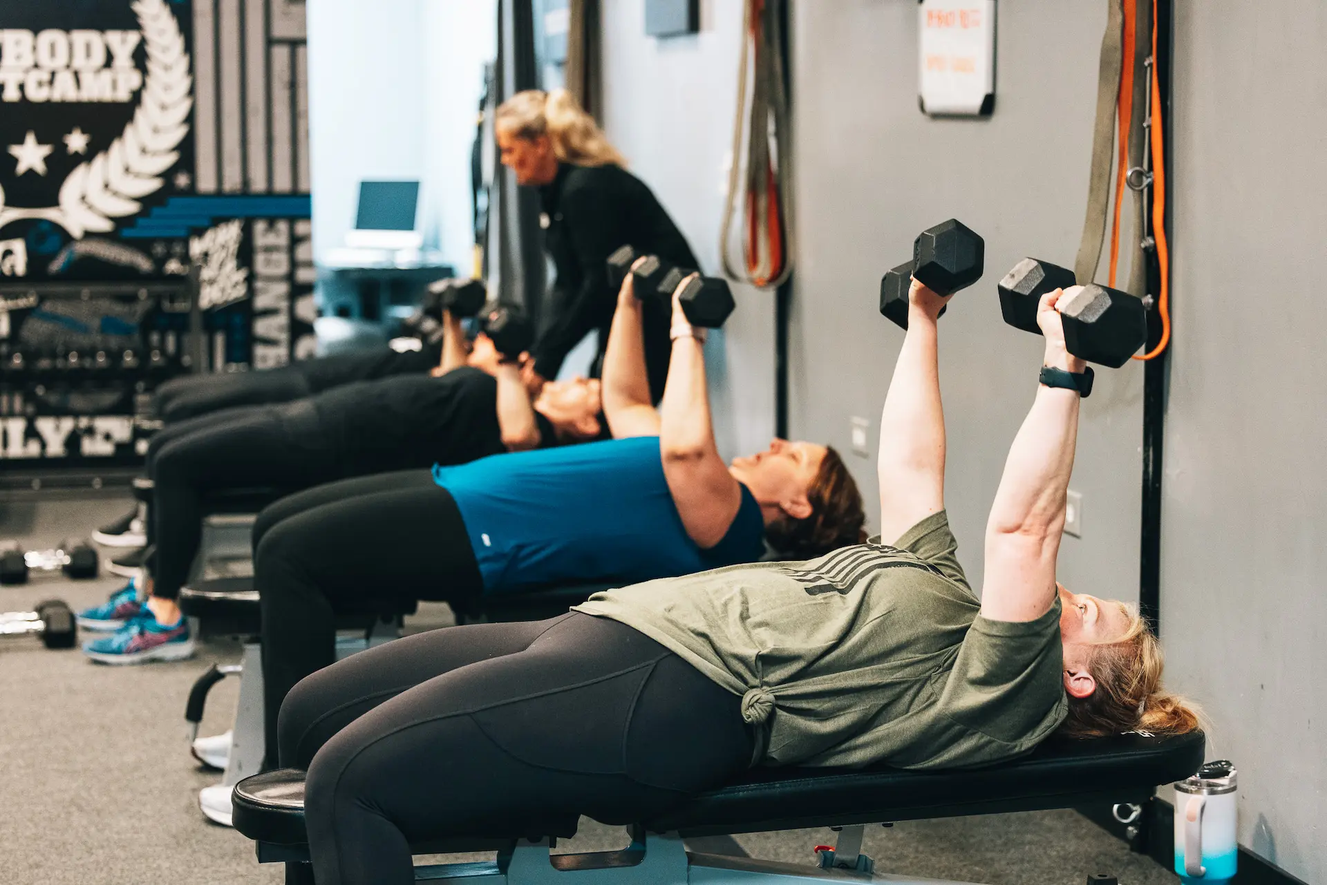 Fit Body Boot Camp participants doing a chest press with dumbbells.