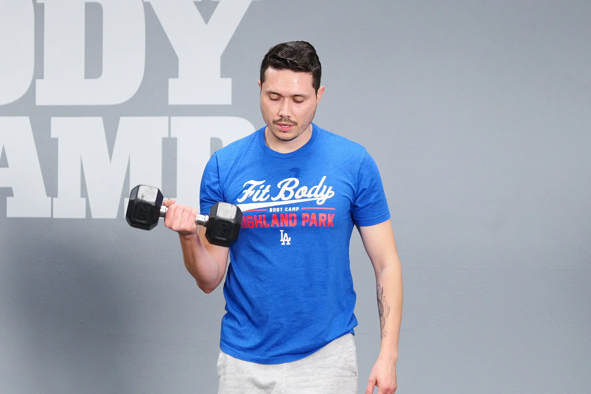 Man performing bicep curls with free weights at Fit Body Boot Camp.