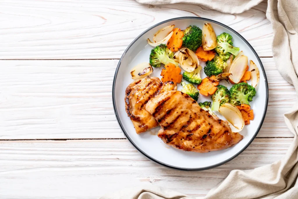 Healthy plate of food with chicken breast broccoli and carrots.