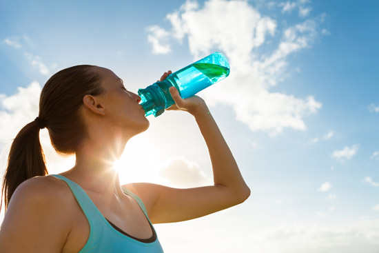 woman drinking a bottle of water after a workout to stay healthy