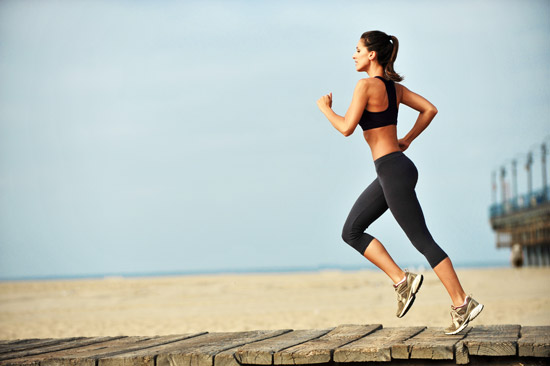 A young woman living a healthy lifestyle running along the beach boardwalk